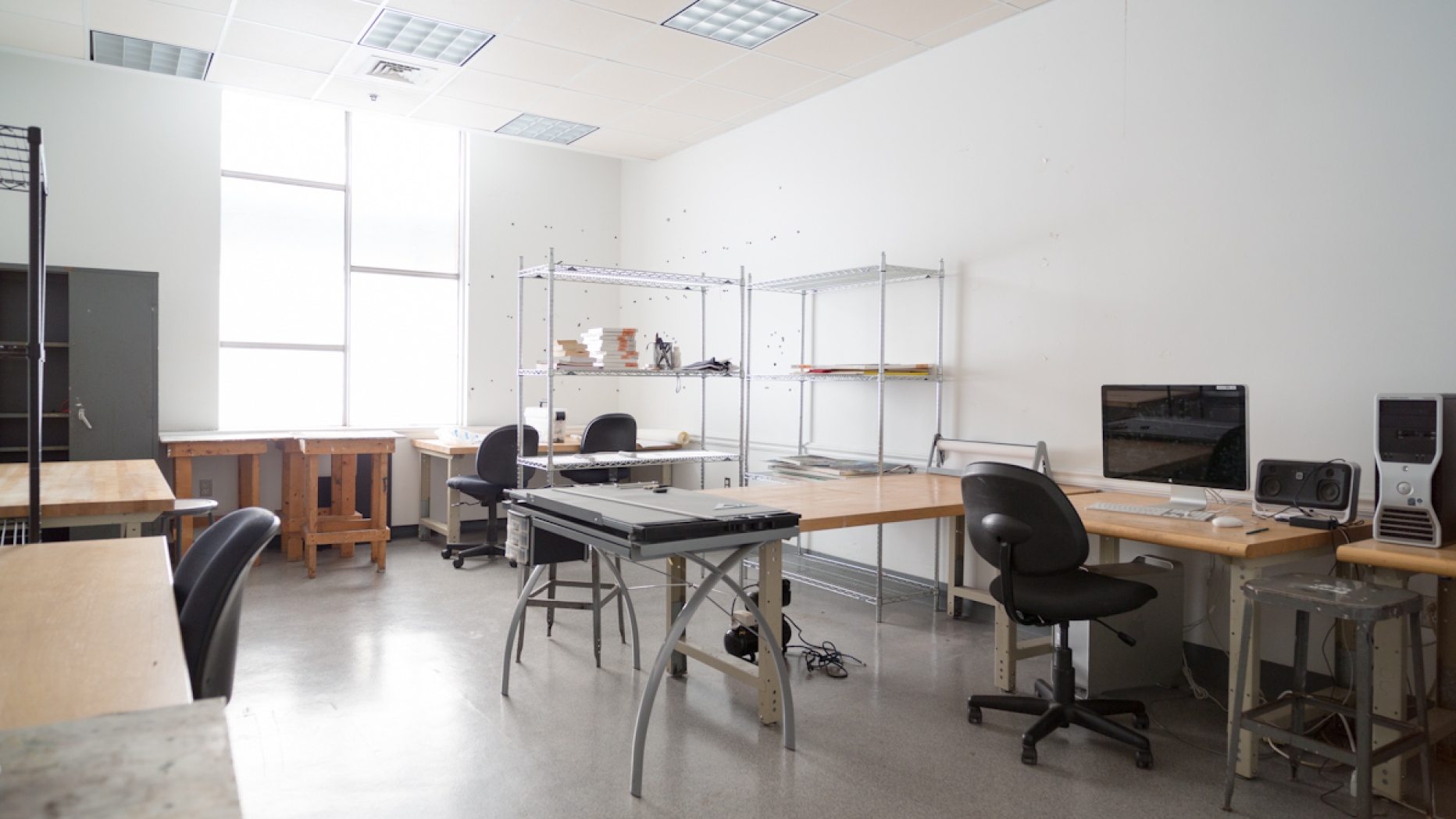 Unoccupied office/studio space with several computers and a work table in the center.