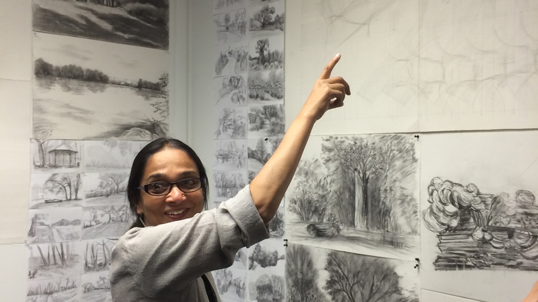 Anu Mathur pointing up a a rendering pinned to a wall