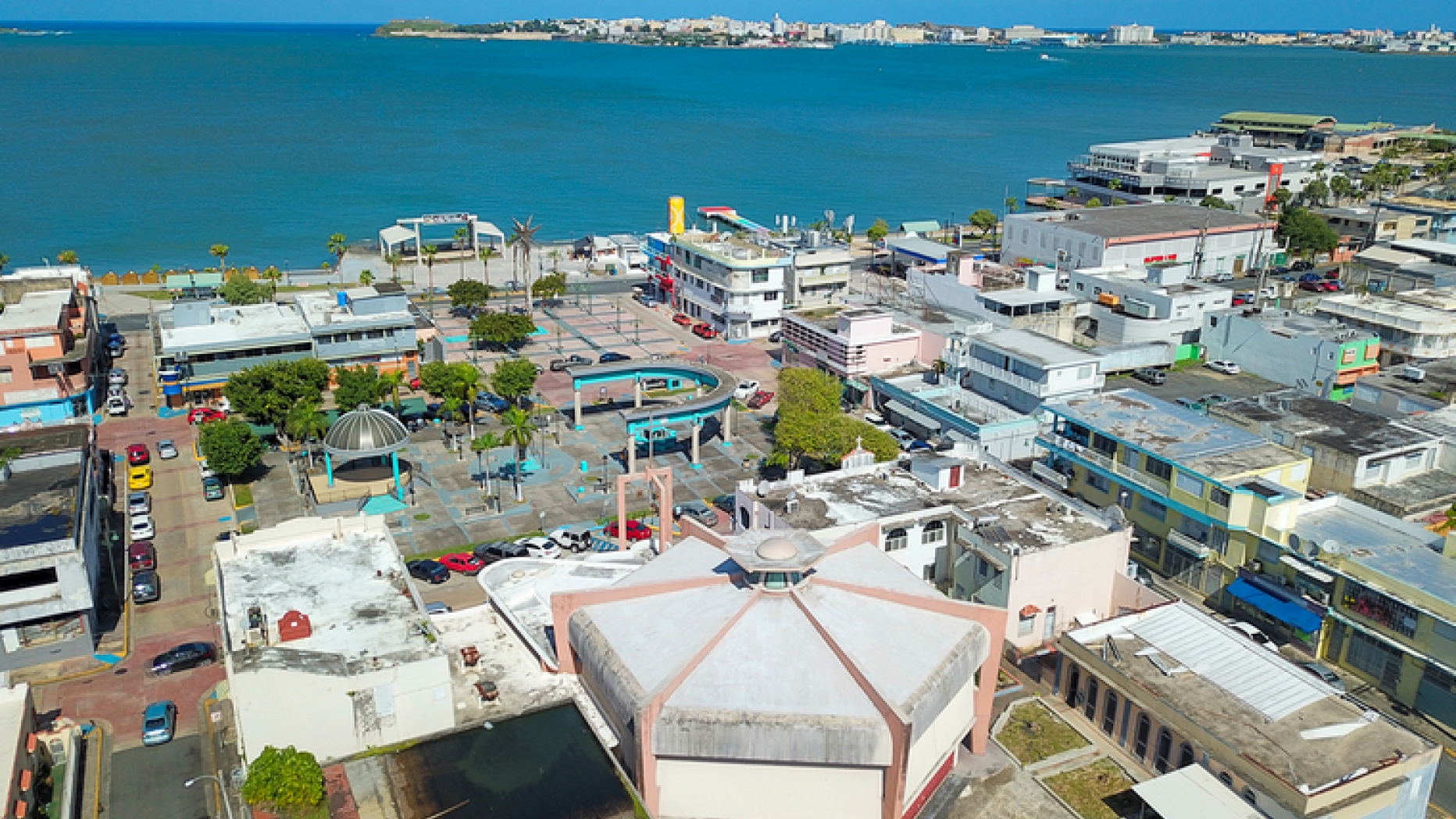 View of The Del Carmen Church from above in front of a plaza & the San Juan bay. 