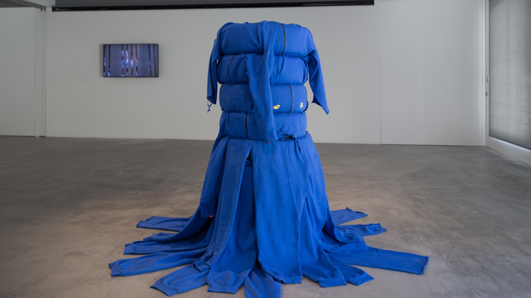 Sculpture featuring blue track suits wrapped around a stack of car tires.