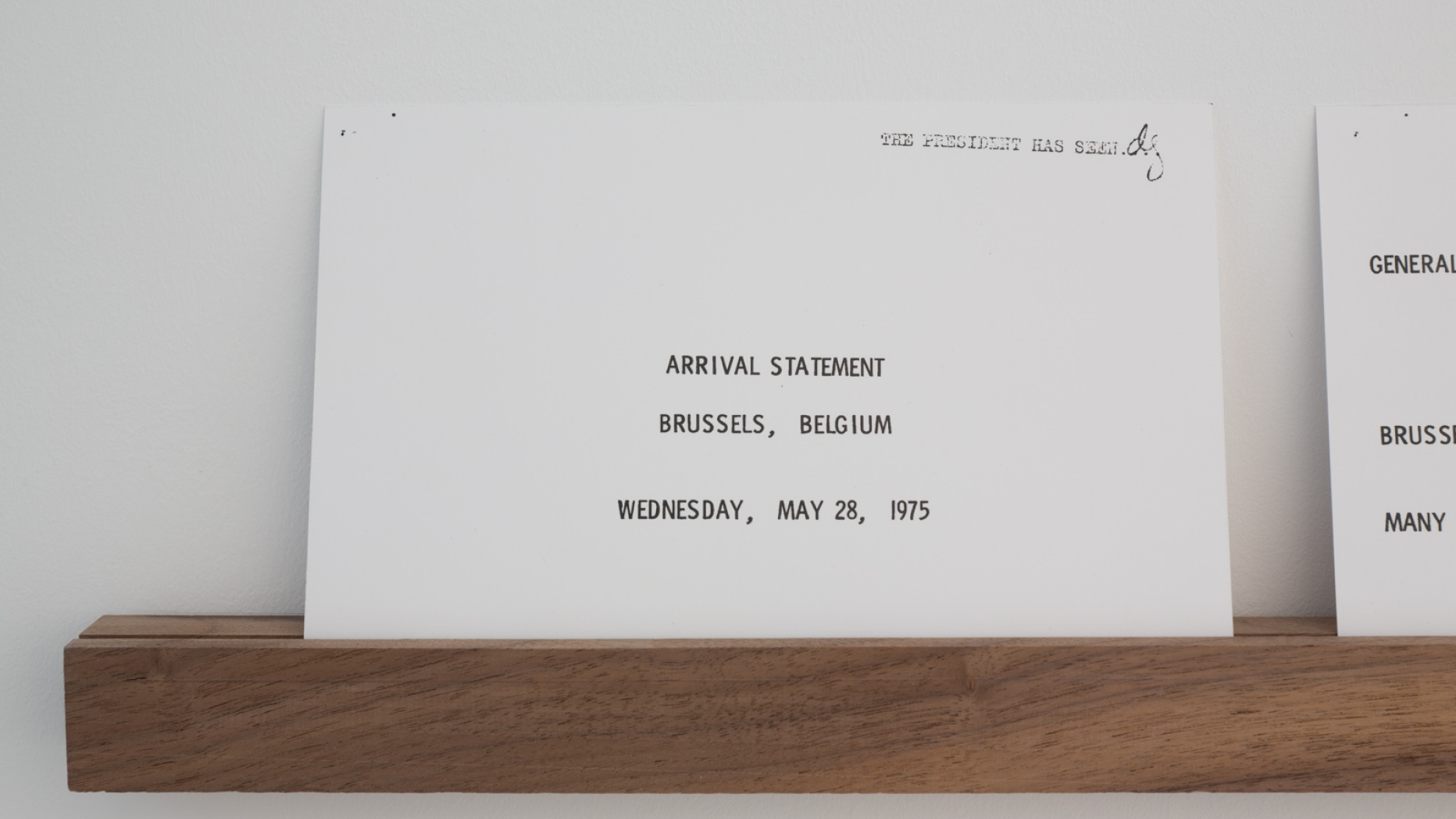 Card with text "Arrival Statement. Brussels, Belgium. Wednesday, May 28, 1975"