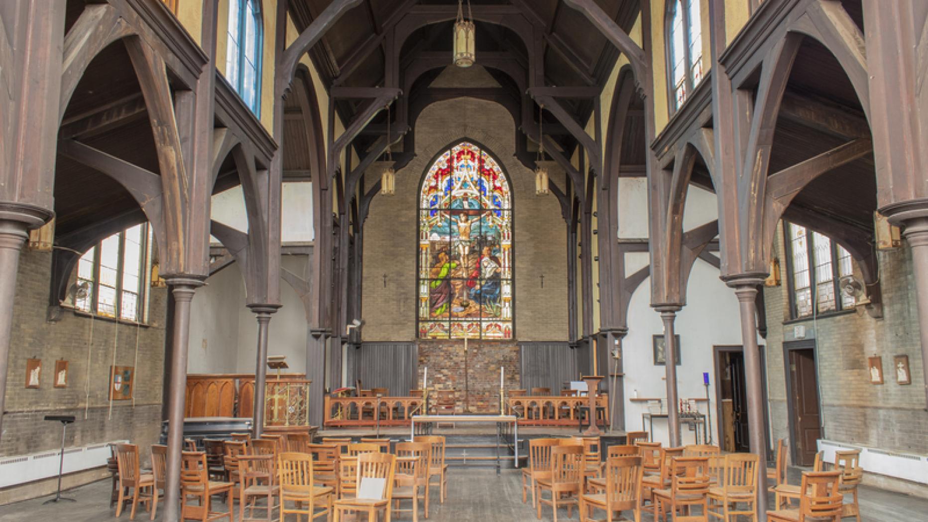 Interior of a Church with wood arches and a colorshop stained glass altarpiece 