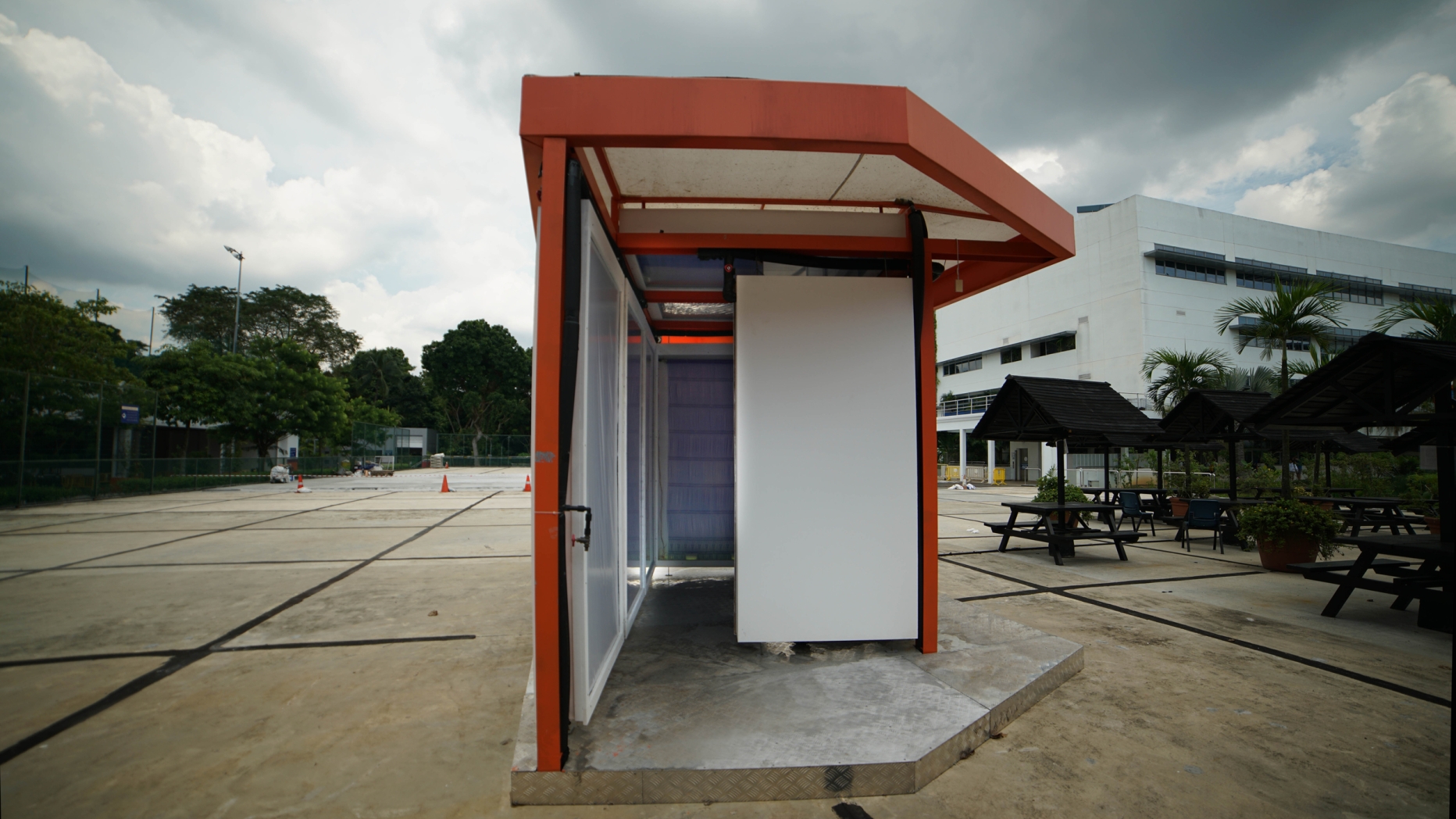 A radiant cooling pavilion with orange-painted steel frame and panelize walls in a site in Singapore