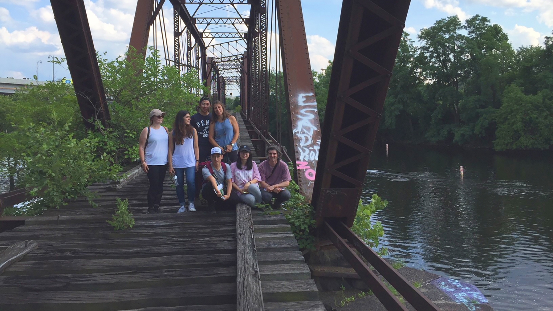 A group of people posing on a train bridge