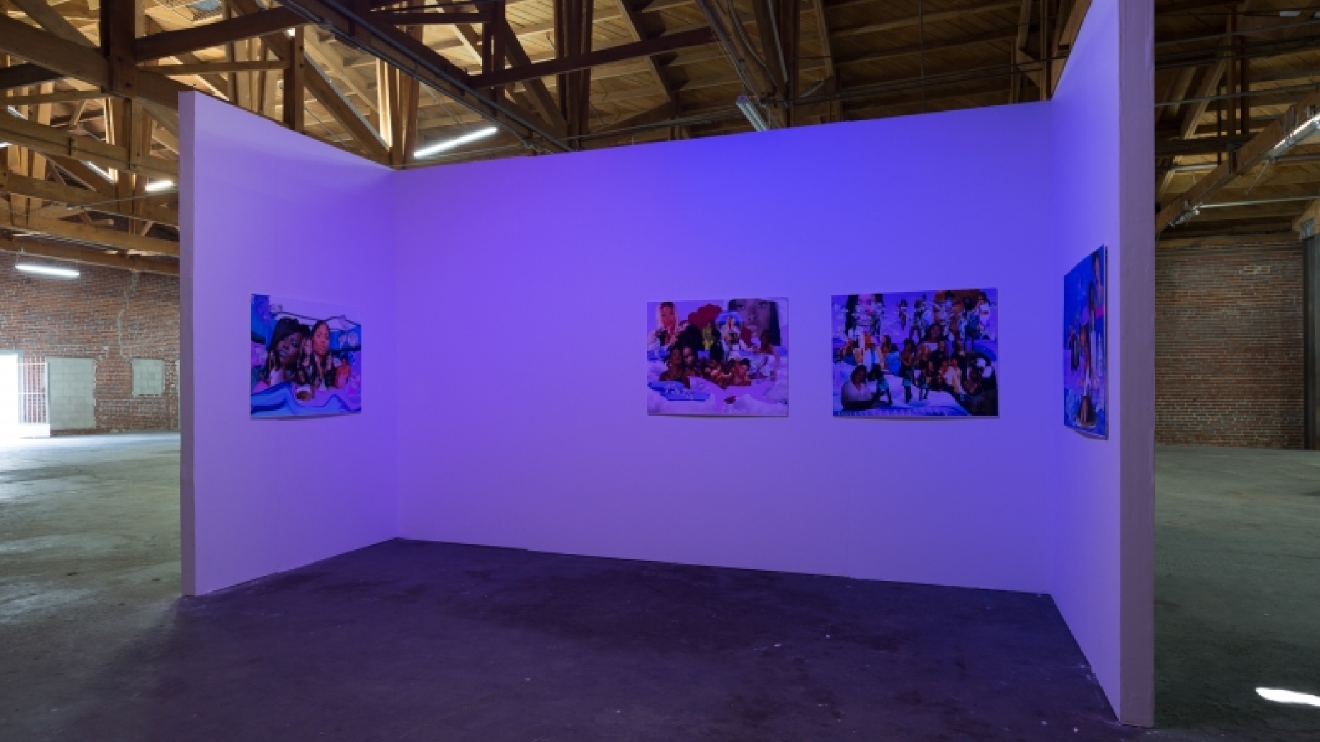 Section of gallery with purple lighting and art work on the walls.