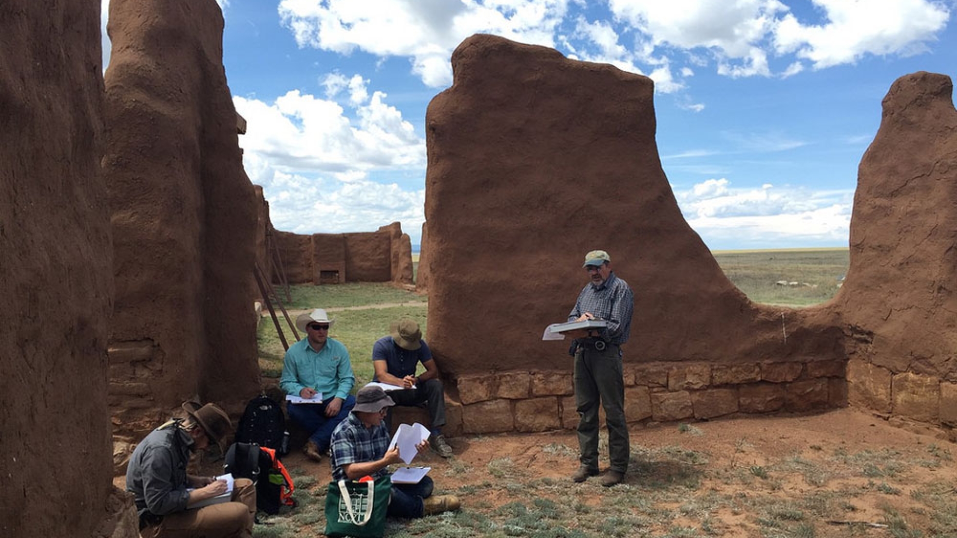 Conservation team sitting amongst adobe ruins at fort union