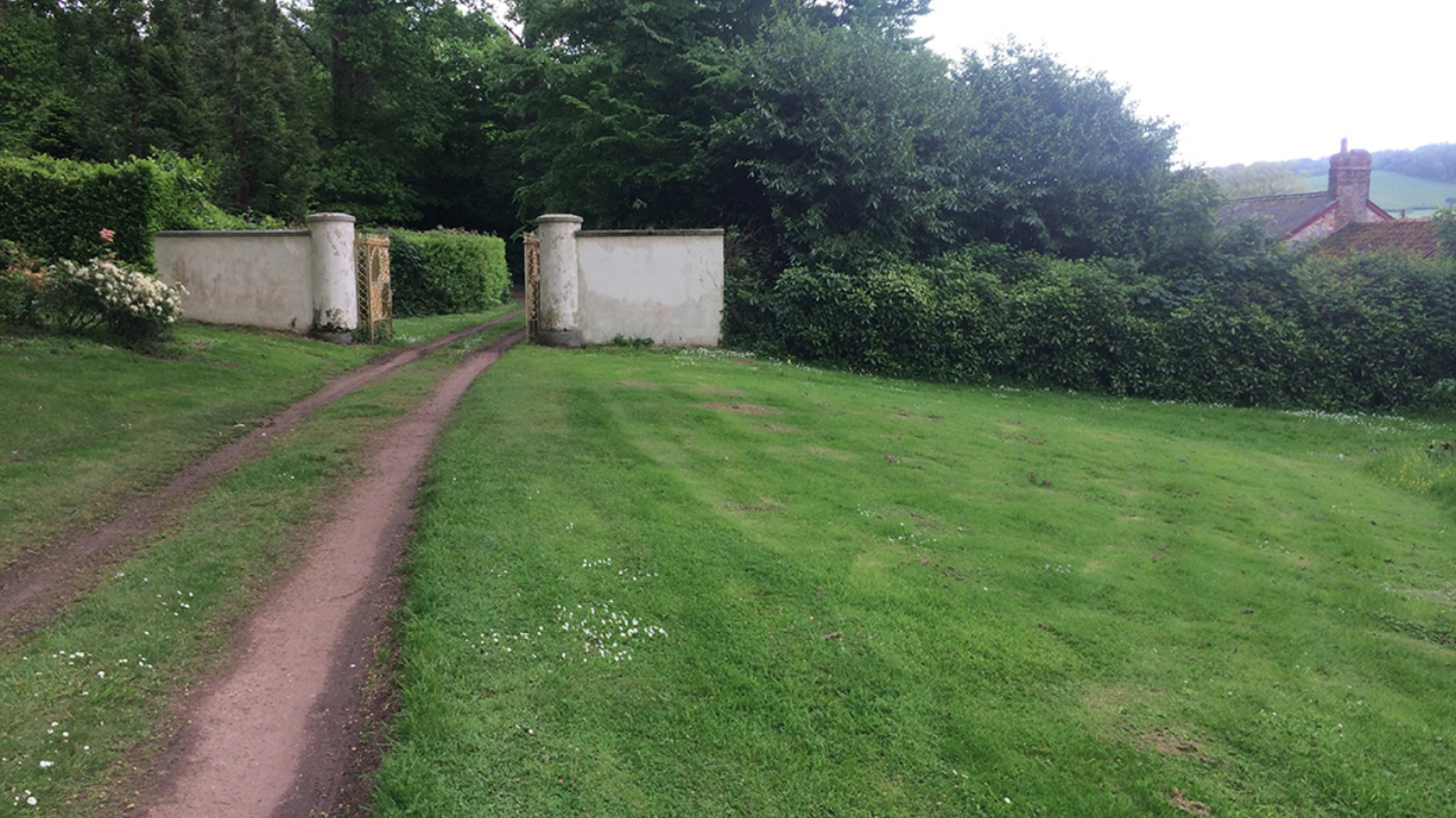 Carriage trail leading to garden entrance framed with two white pillars