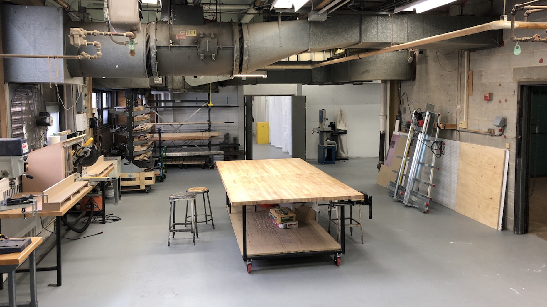 Unoccupied studio space with table in center and supplies and smaller work tables on the sides.