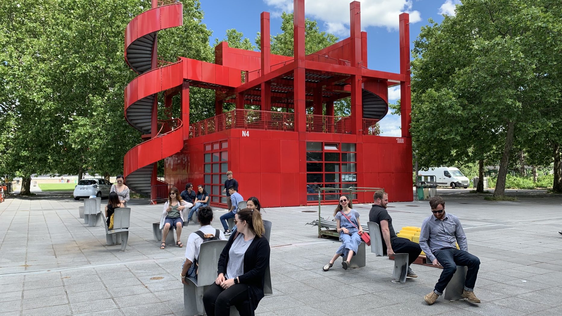 Red metal building with eccentric structure and outdoor seating area
