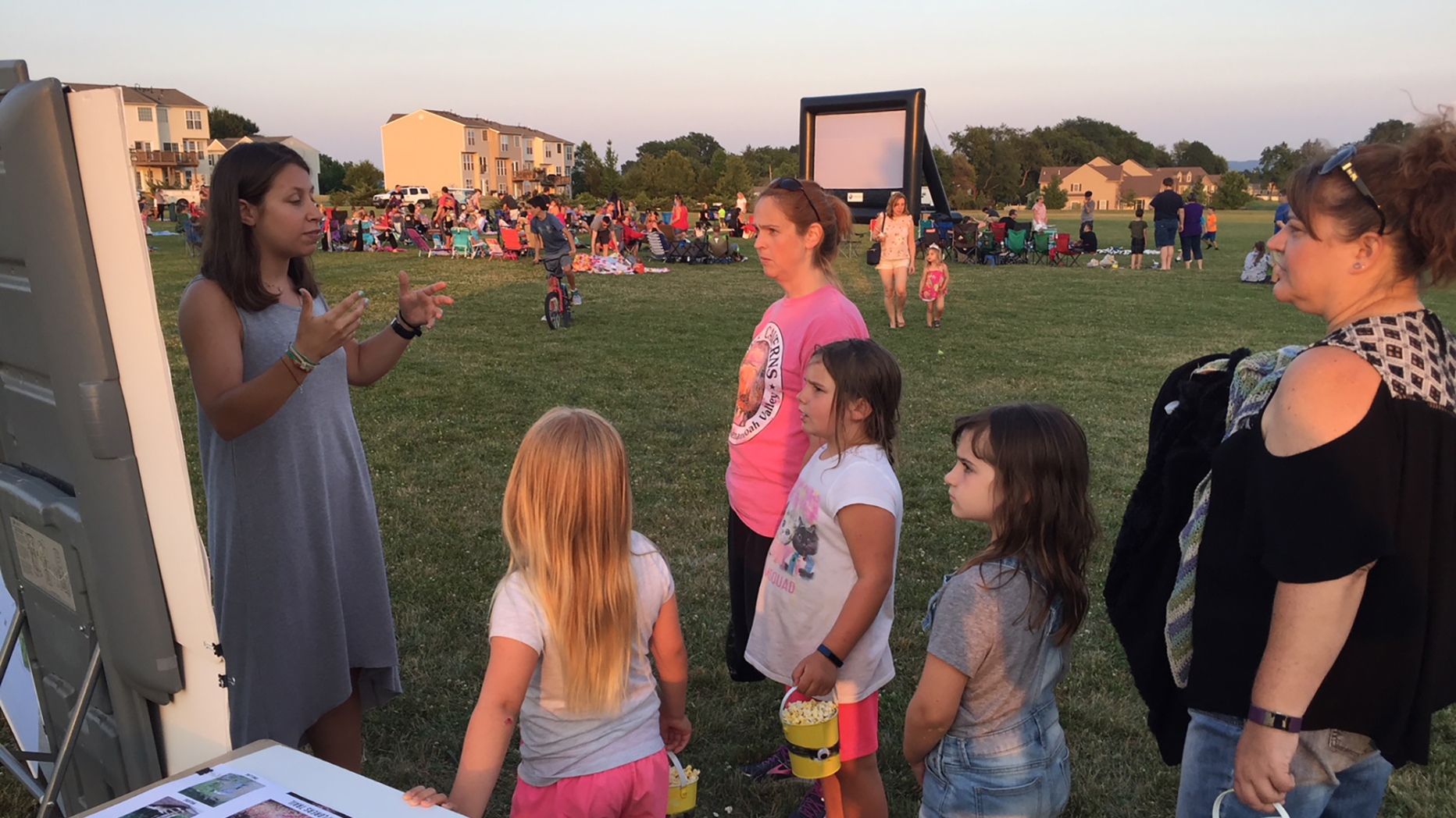 A person speaks to a group of people at an outdoor event