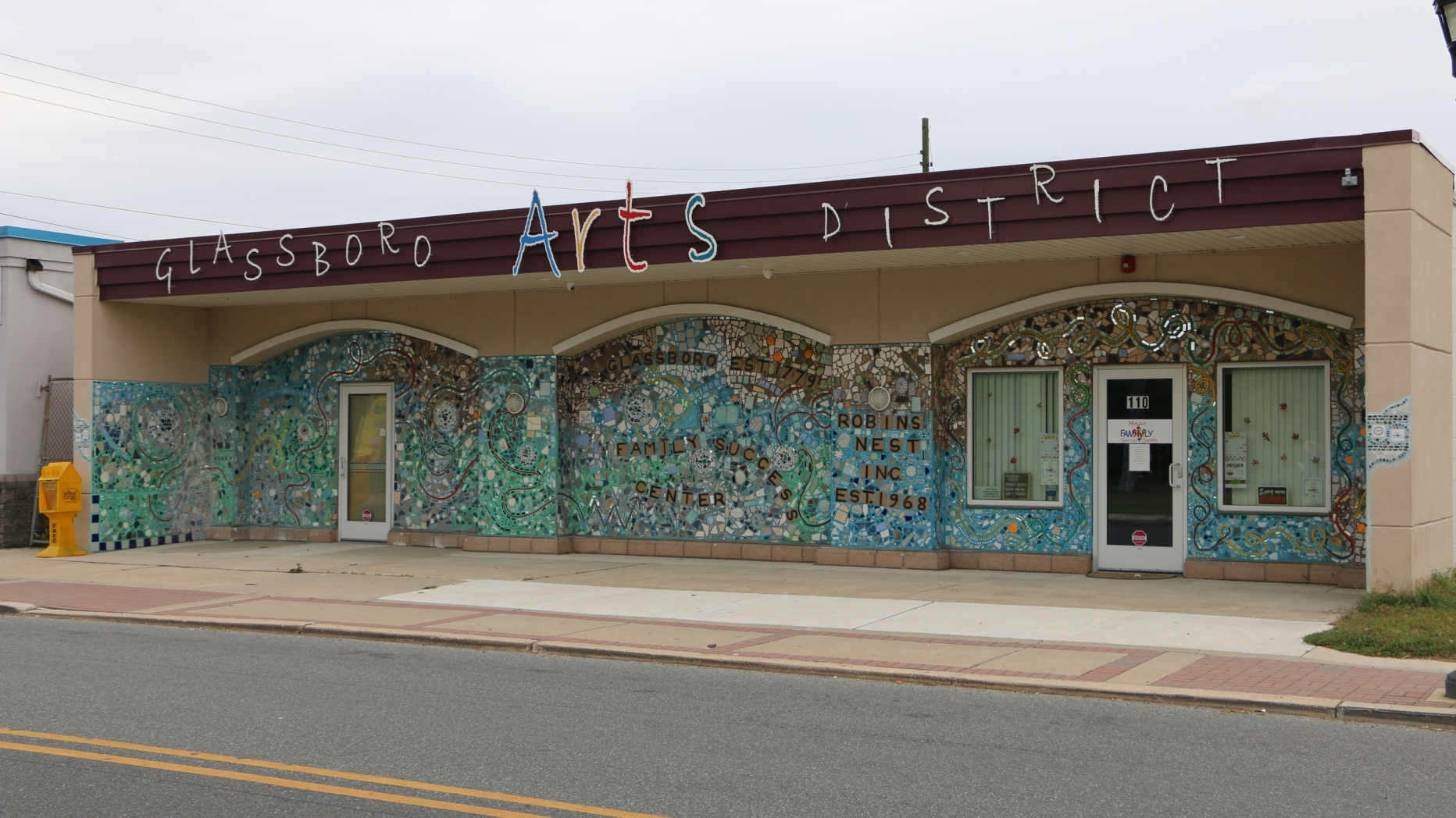 Building covered in turquoise mosaic with sign saying Glassboro Arts District