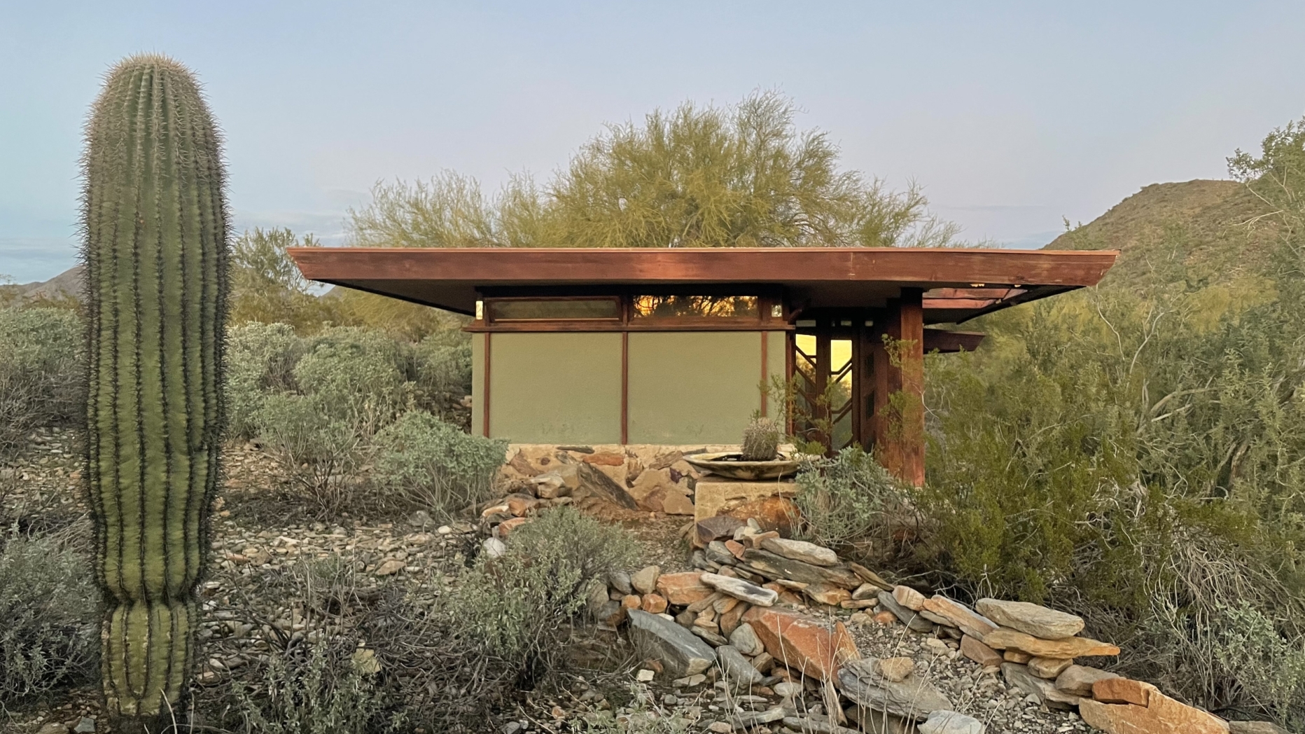 small modernist structure in desert with cactus in foreground