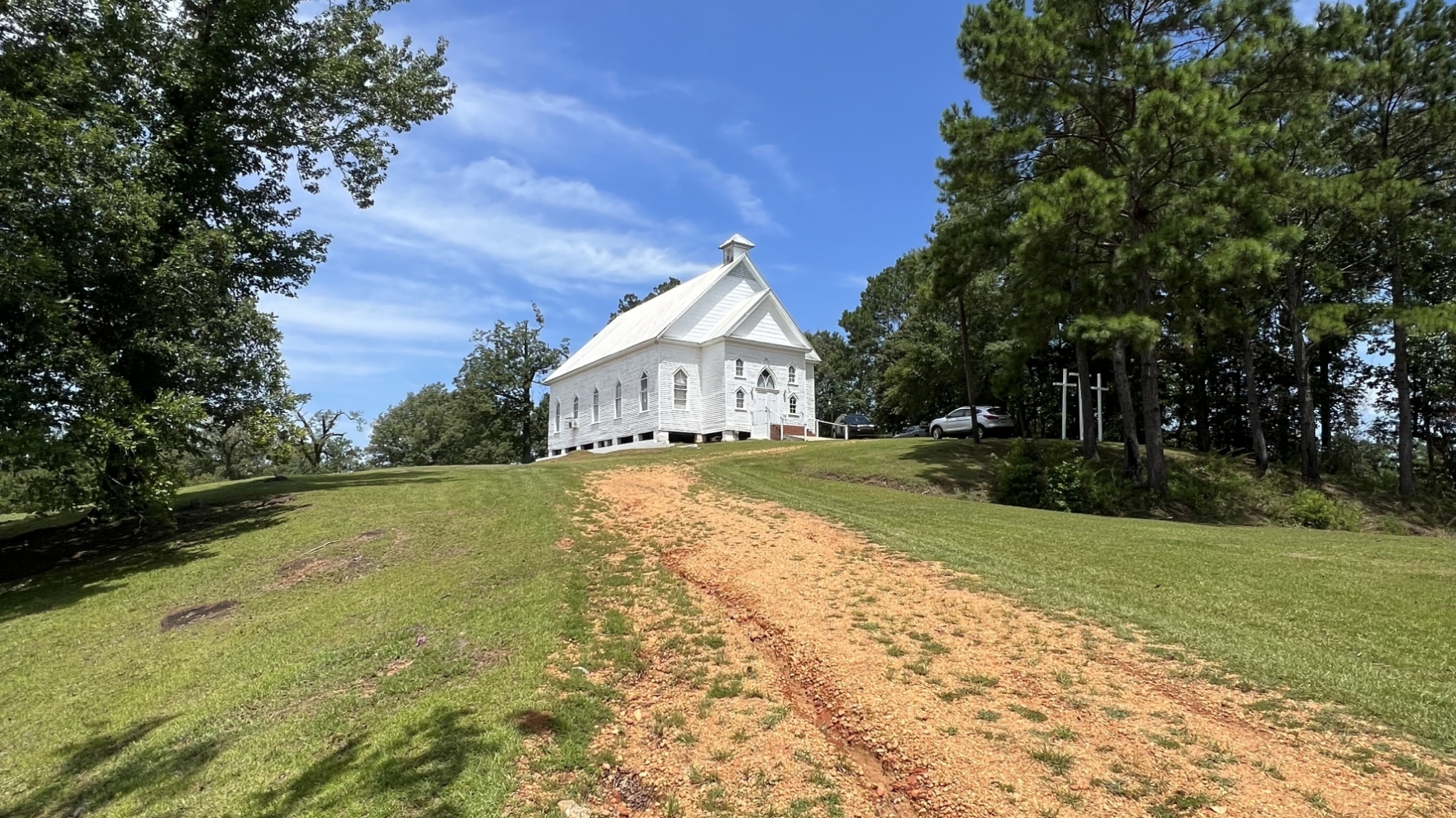 white church building, dirt path, and trees