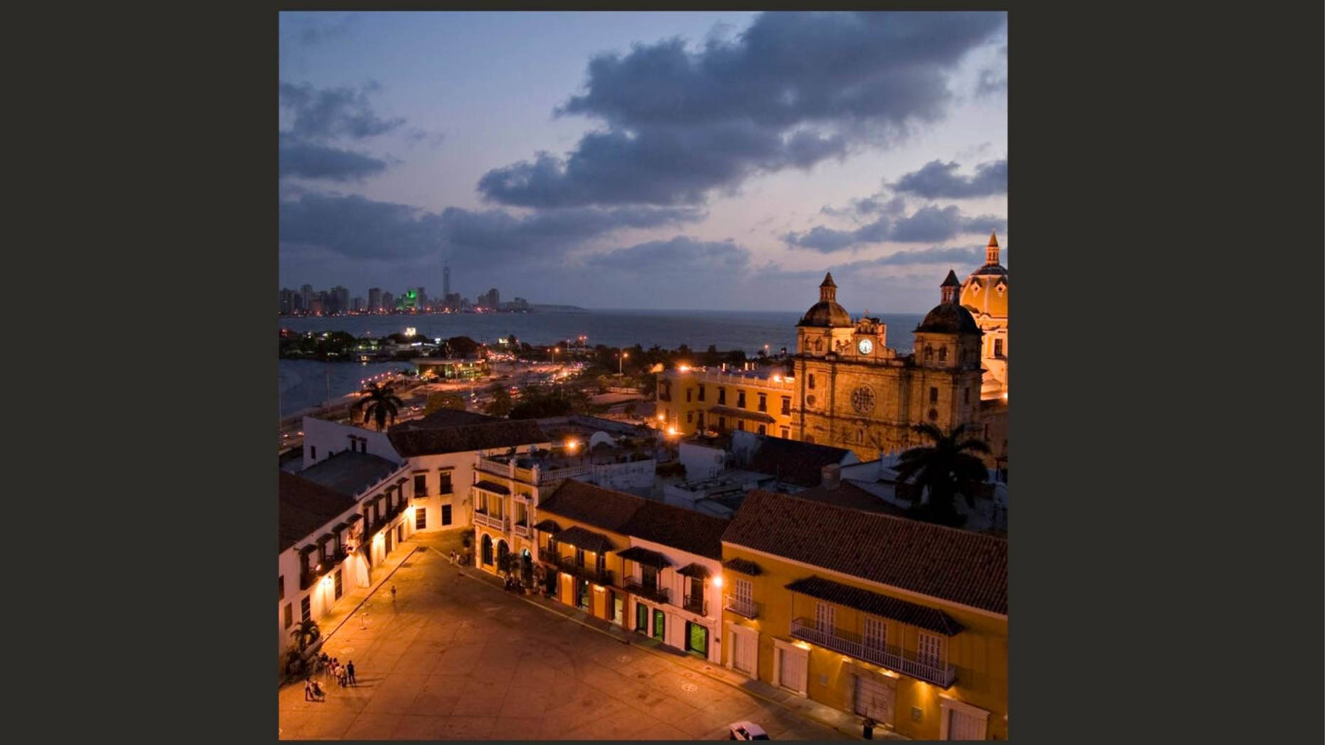 Cartagena historic fort lit up at night with modern city in background