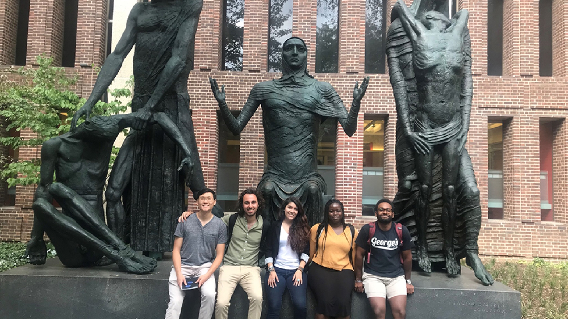 5 diverse individuals with statues of human suffering in the background