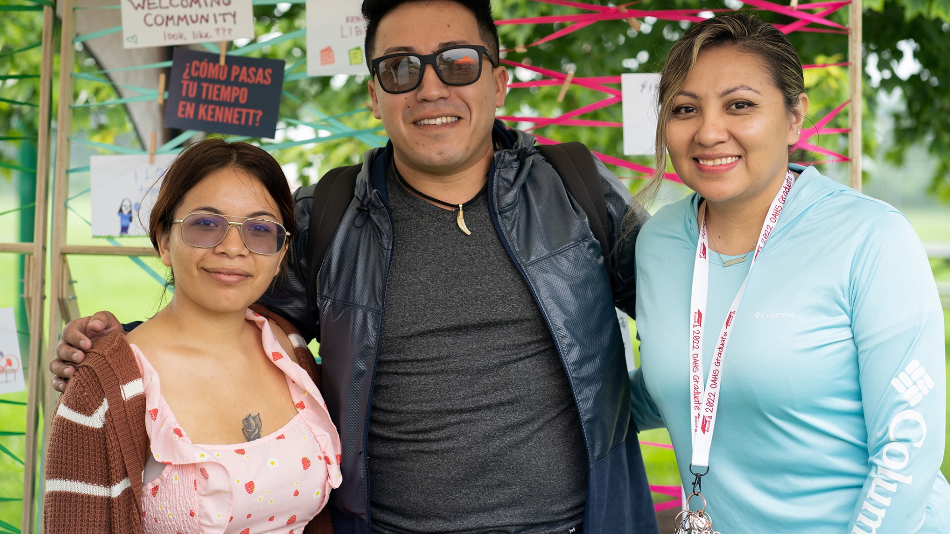 Three people stand together posing for the camera