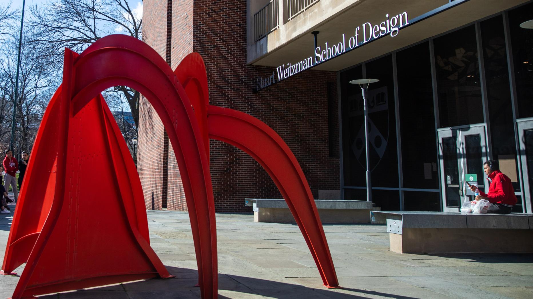 Red metal sculpture in front of Brutalist facade of Meyerson Hall