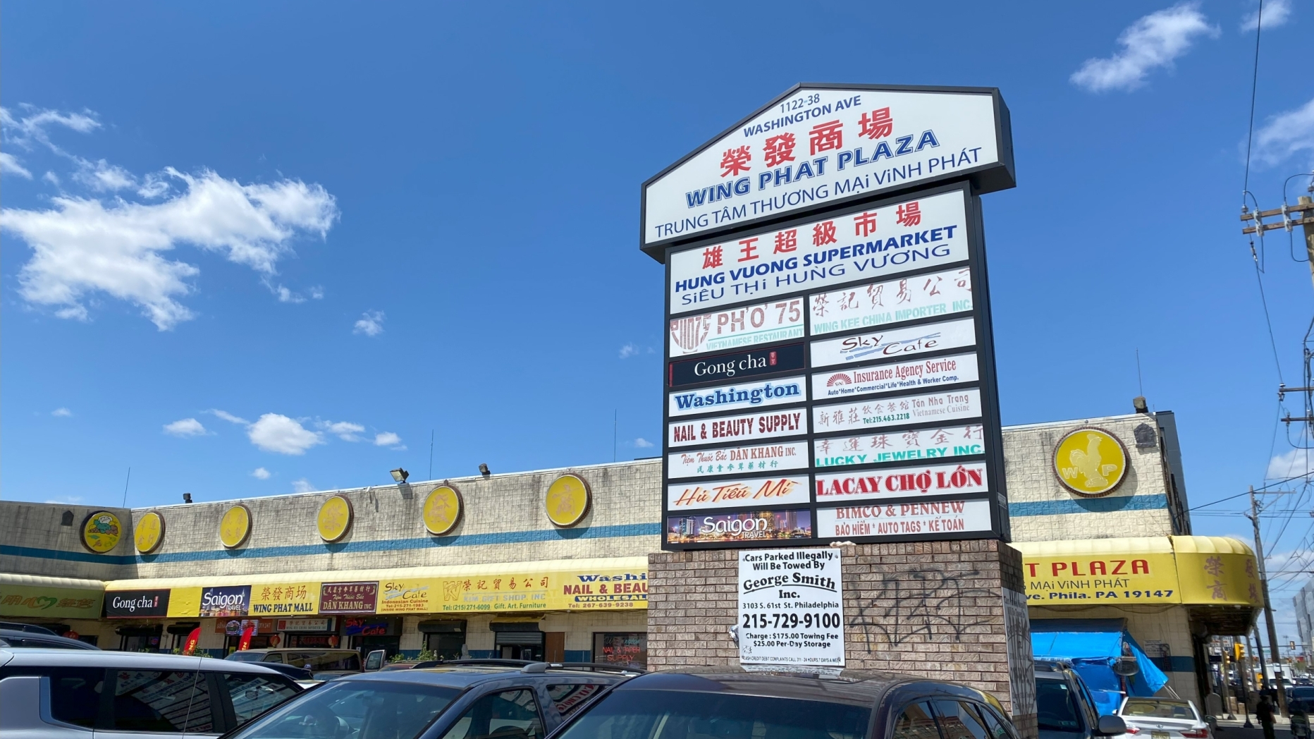 large sign in parking lot of strip mall with yellow awnings