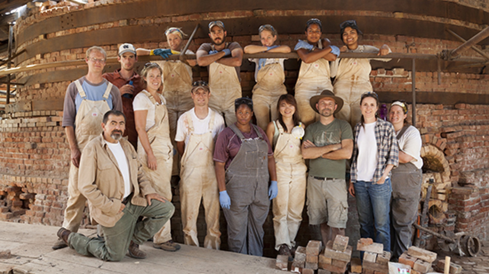 Group photo of project participants in front of scaffolding and brick structure.