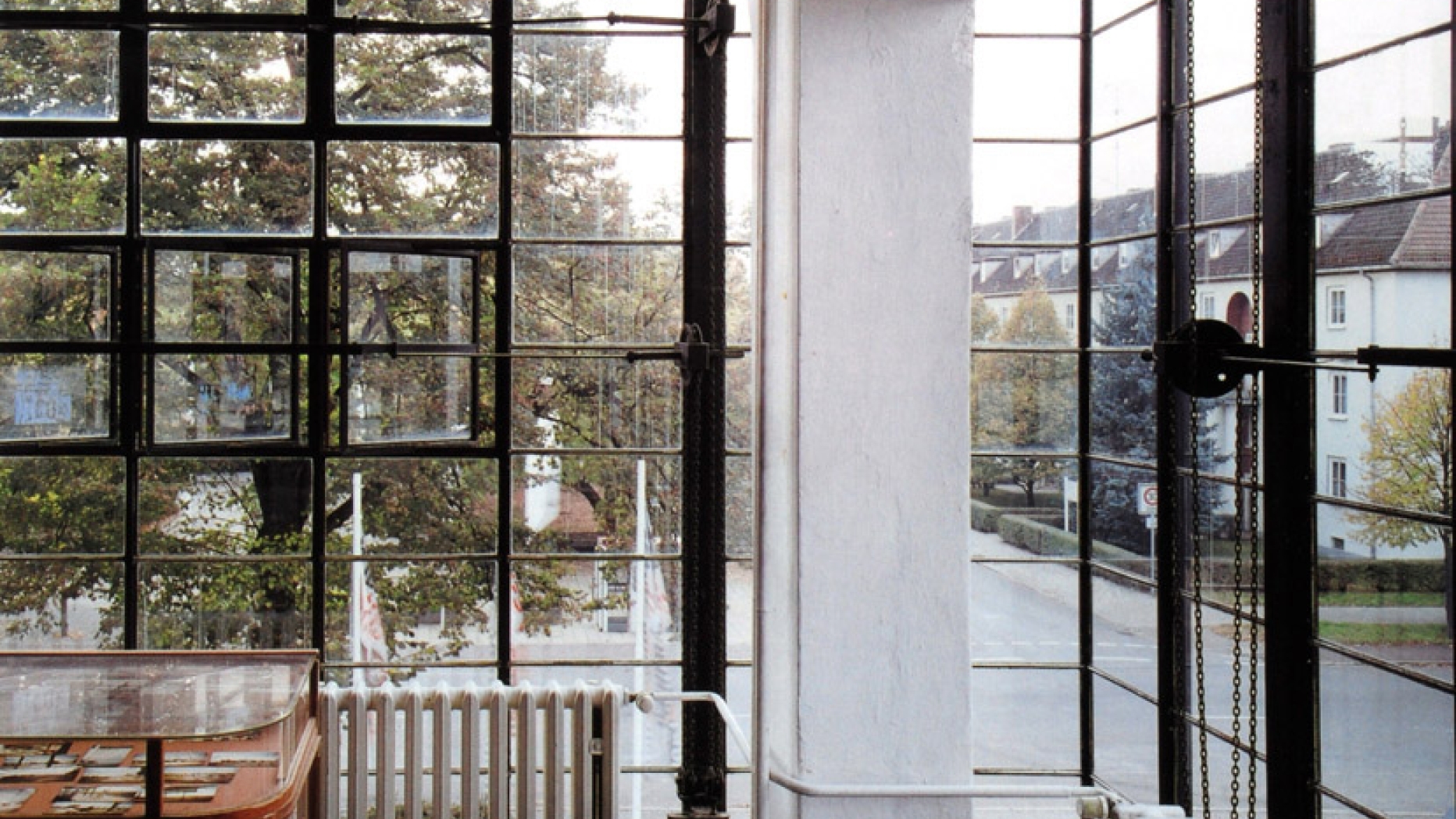 Modernist office with large multipaned windows, antique radiators and curved wooden desk