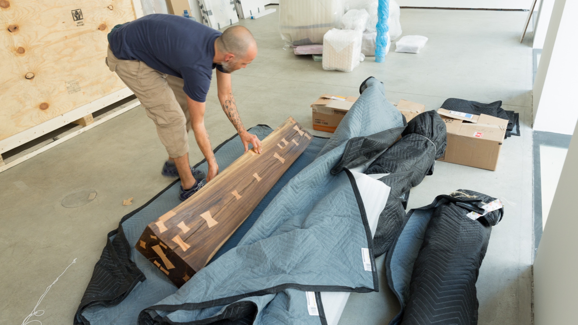 Man taking a large wooden sculpture out of transport packaging.