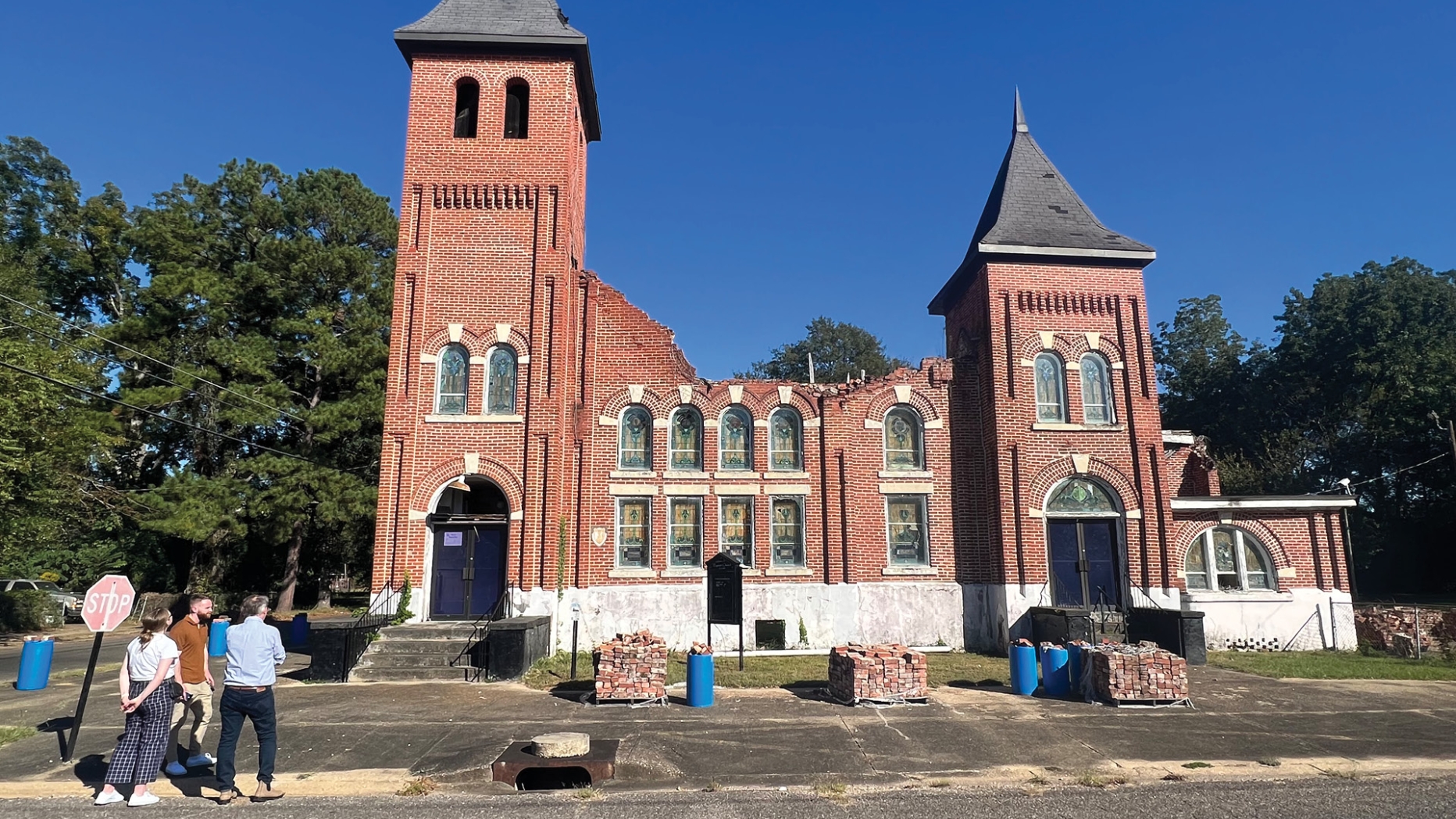 studio team stands in front of partially demolished church