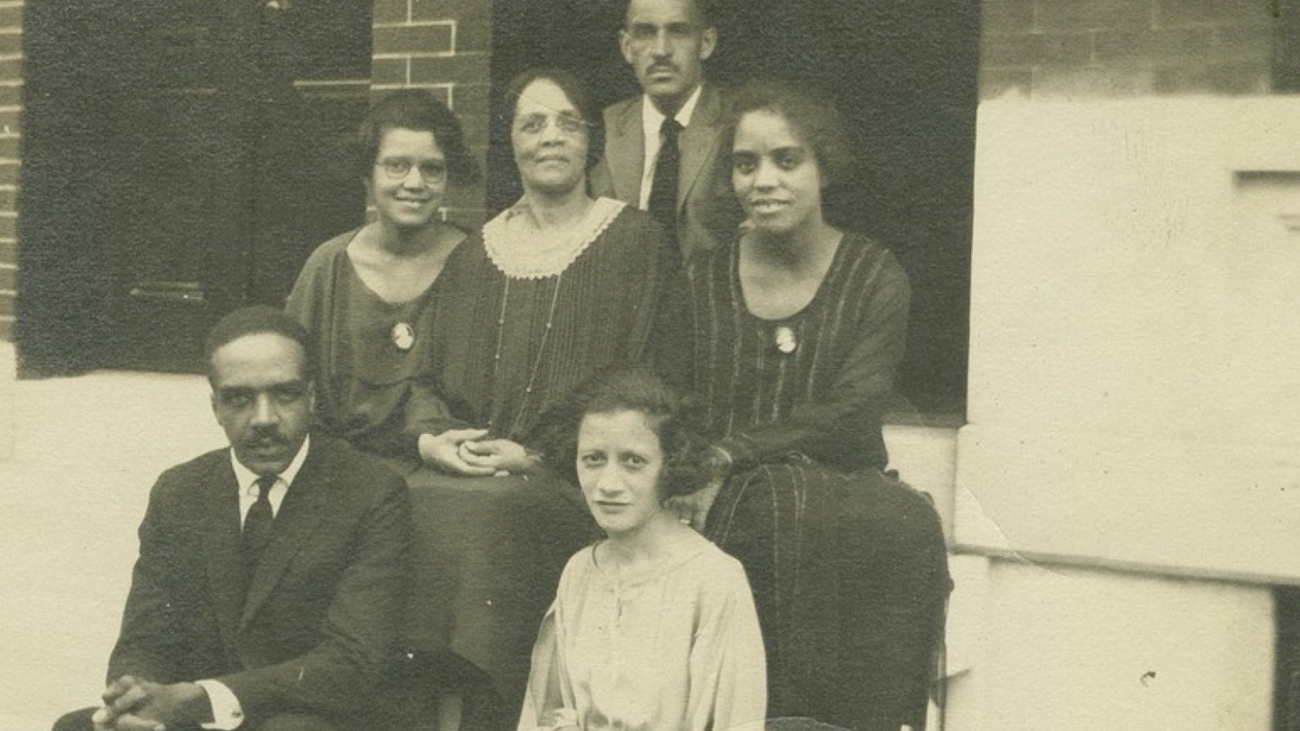 black and white photo of group of people sitting on a stoop