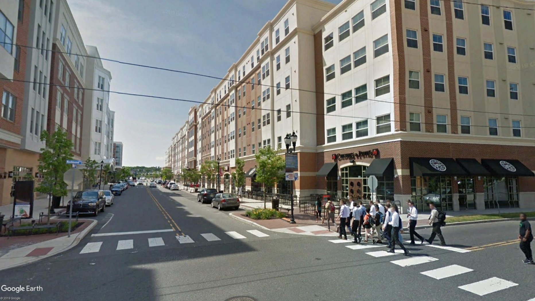 Apartment buildings with shops underneath with people crossing the street