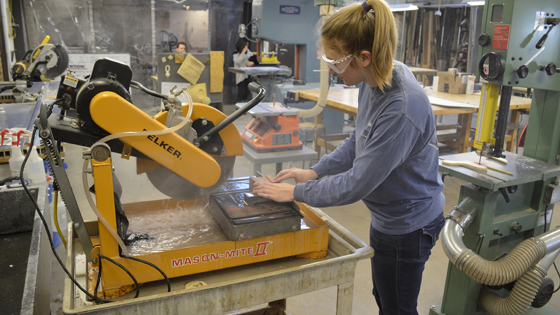 Student working with a piece of heavy cutting machinery.