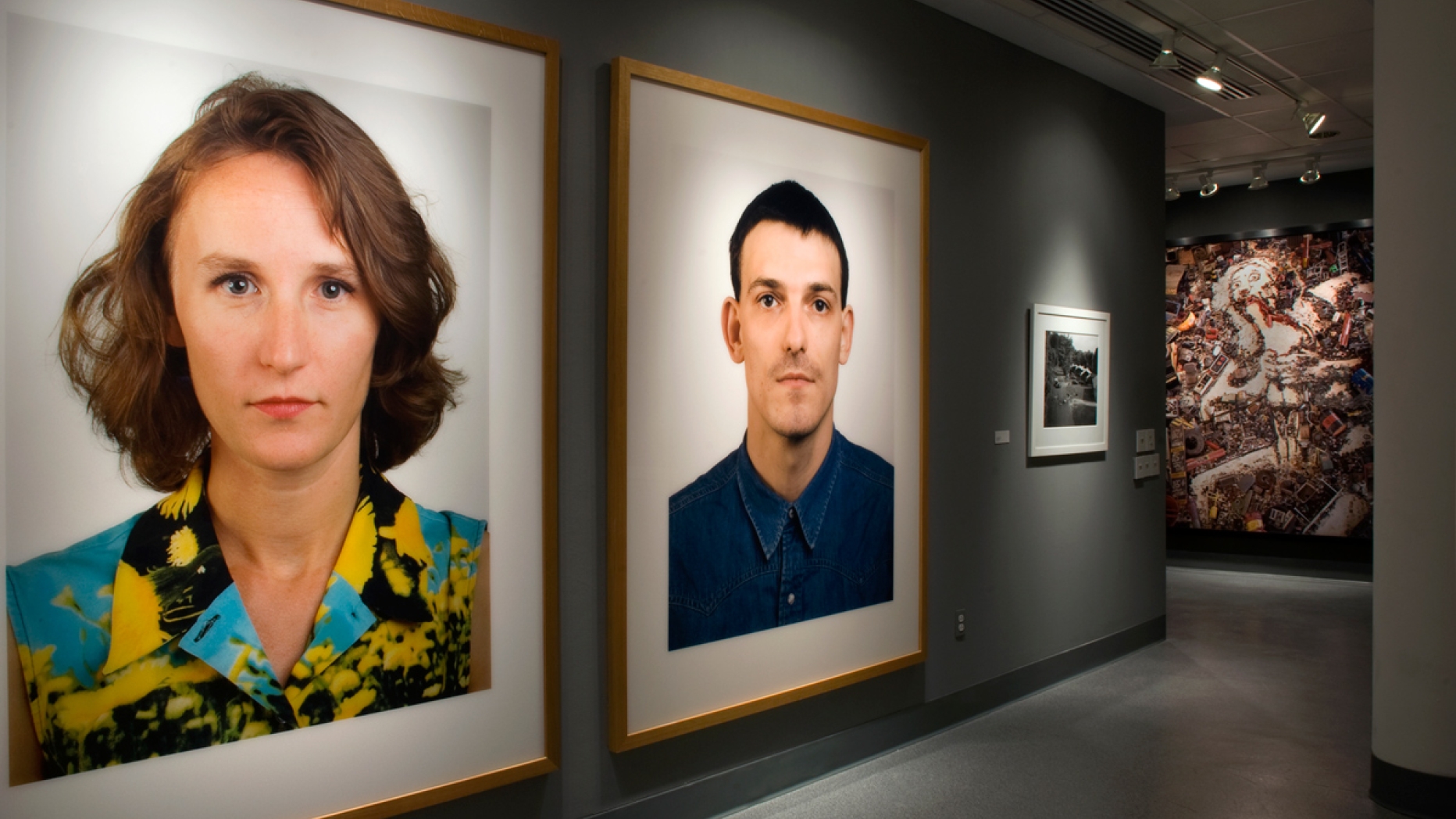 Gallery display of photographs. Most notable pieces are large portraits of a woman and a man.