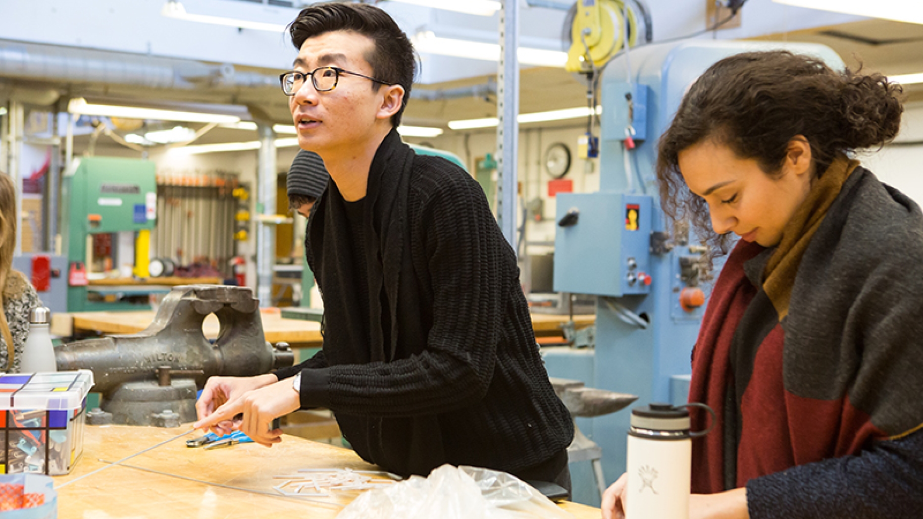 Two students working at table with supplies strewn around