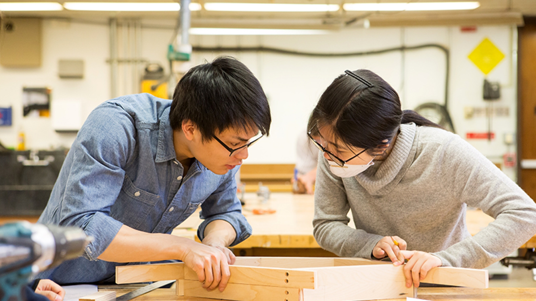Two students working together on a wooden frame a studio
