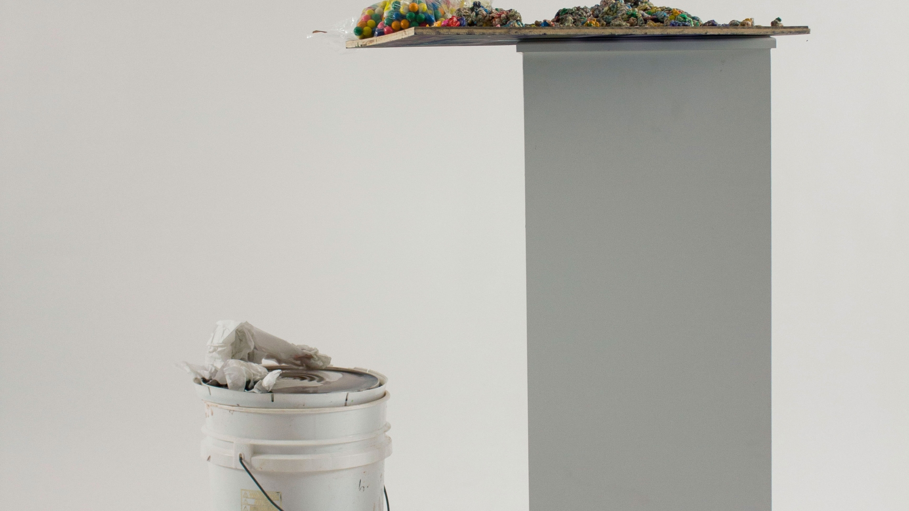 Art piece utilizing various items on a pedestal and a bucket.