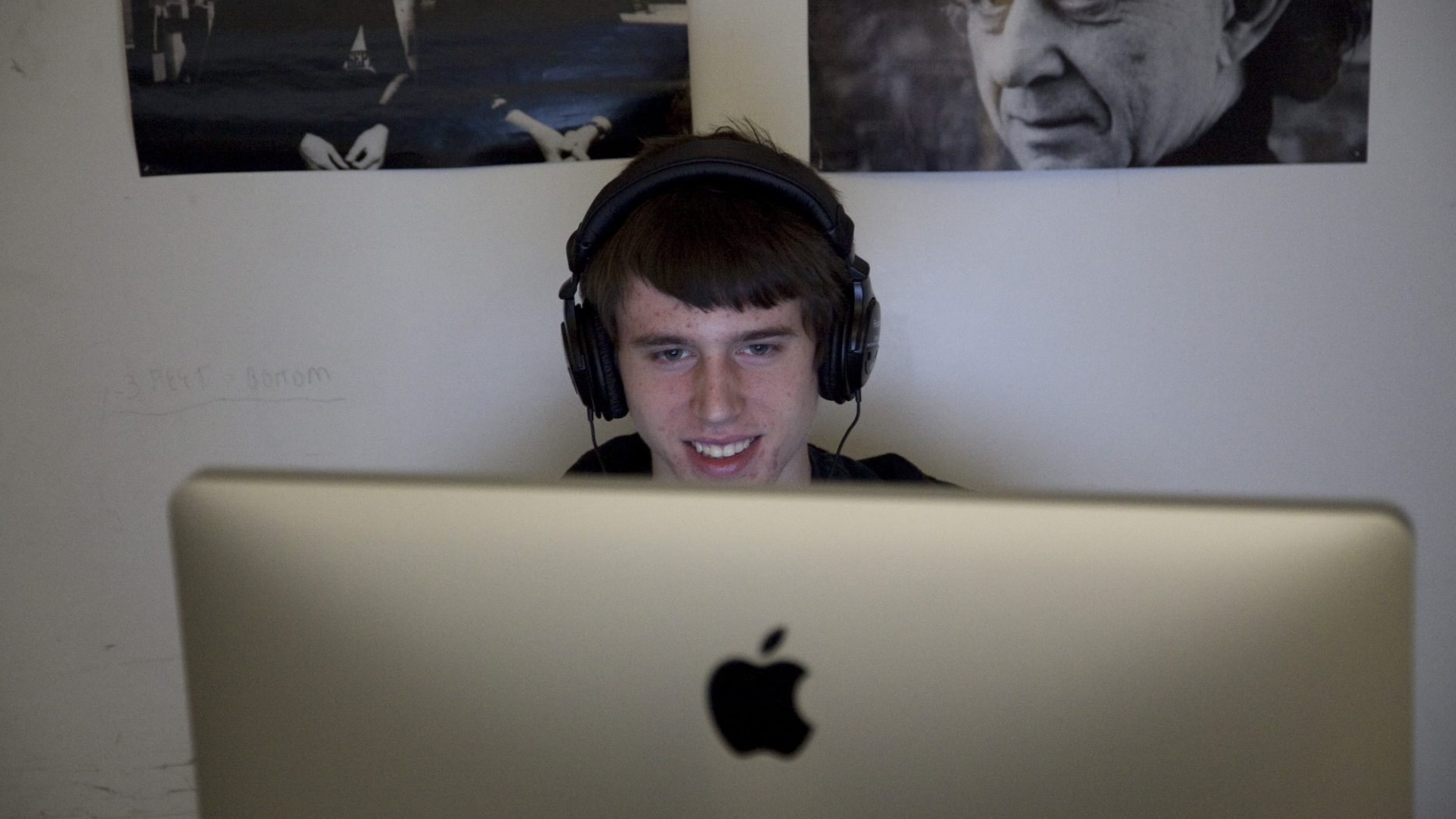 Student wearing headphones looking at a computer and smiling.