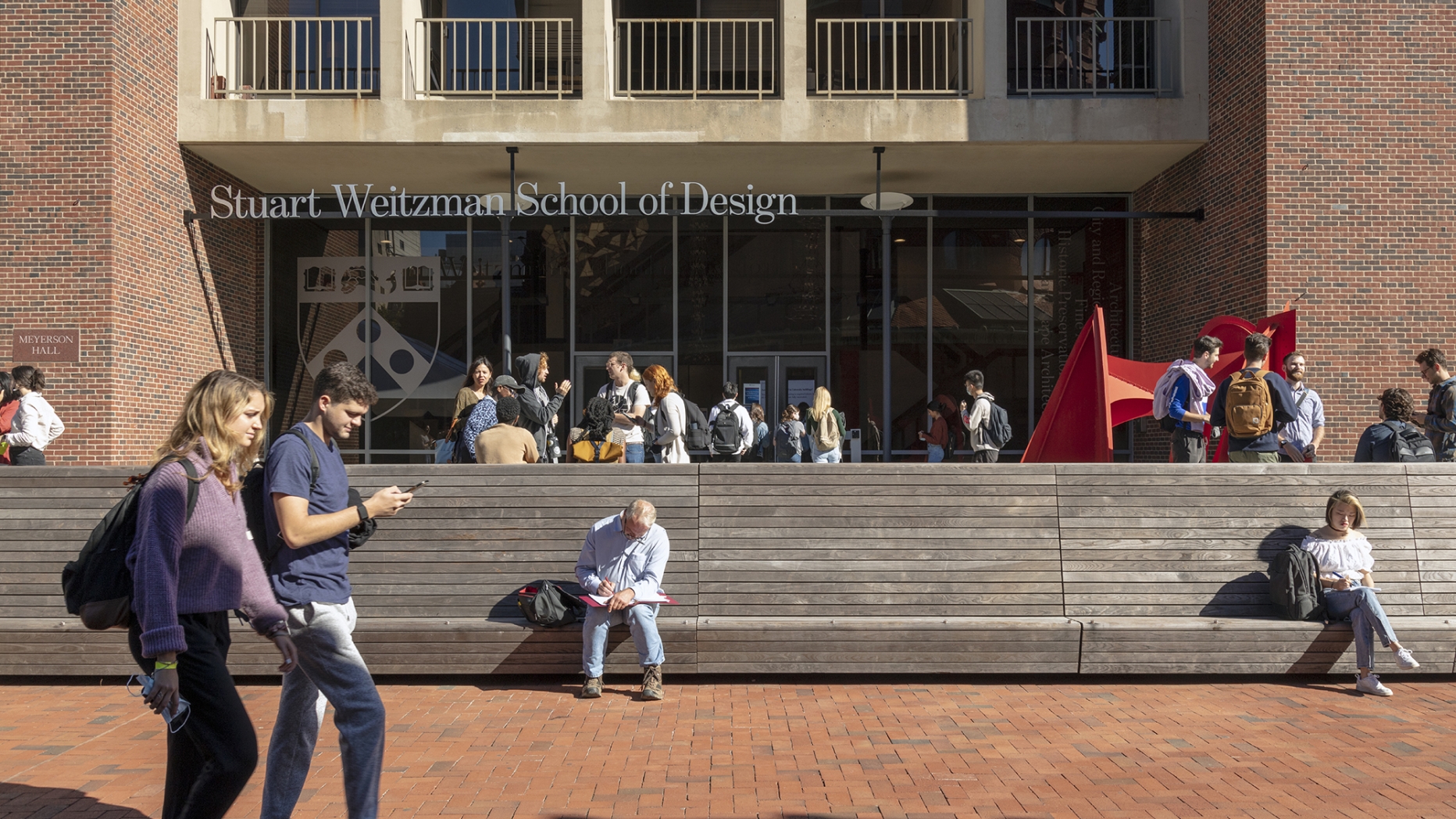 The front of Meyerson Hall with students walking past and standing and talking