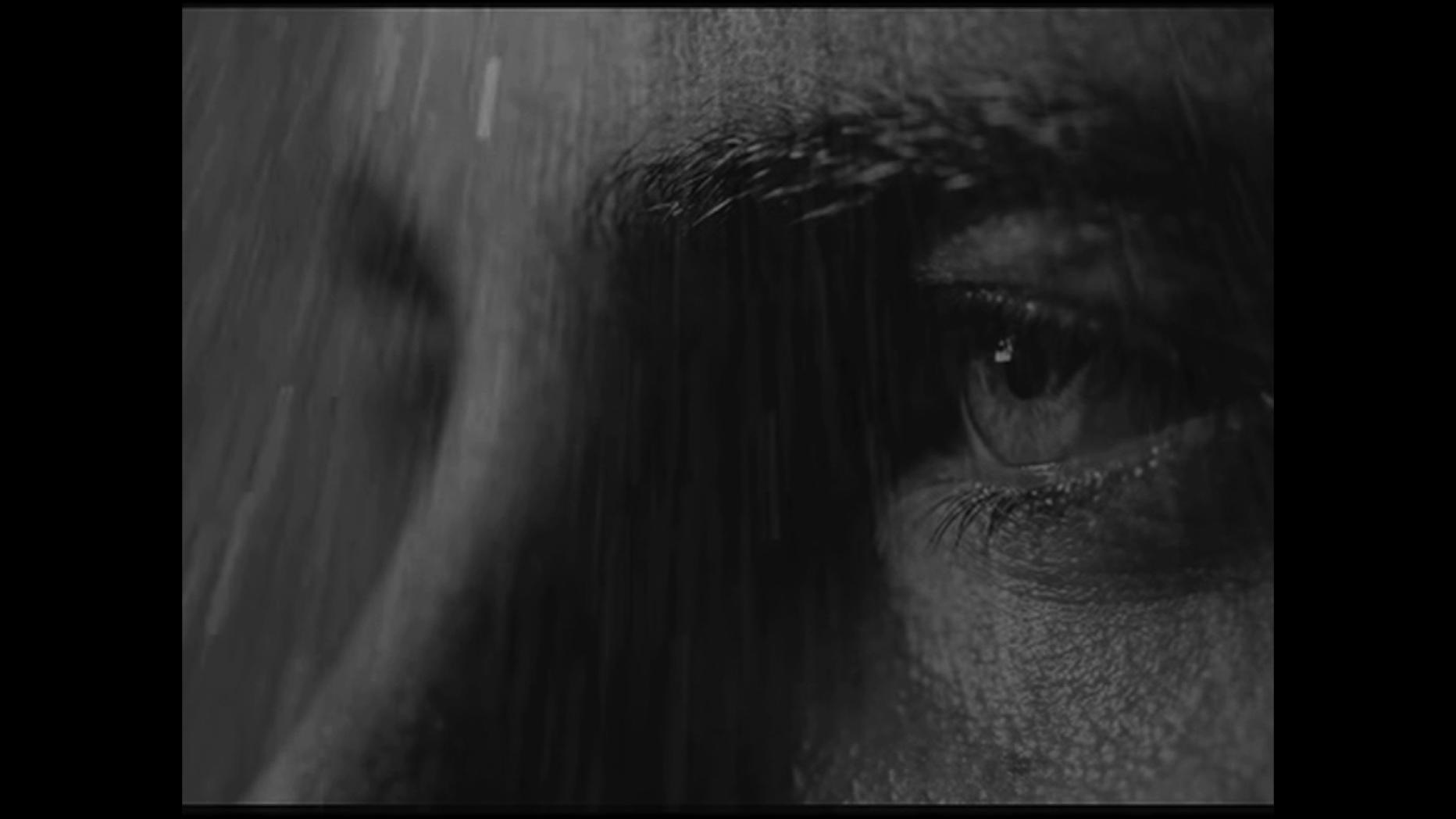 Black and white close up of a man's eyes in the rain.