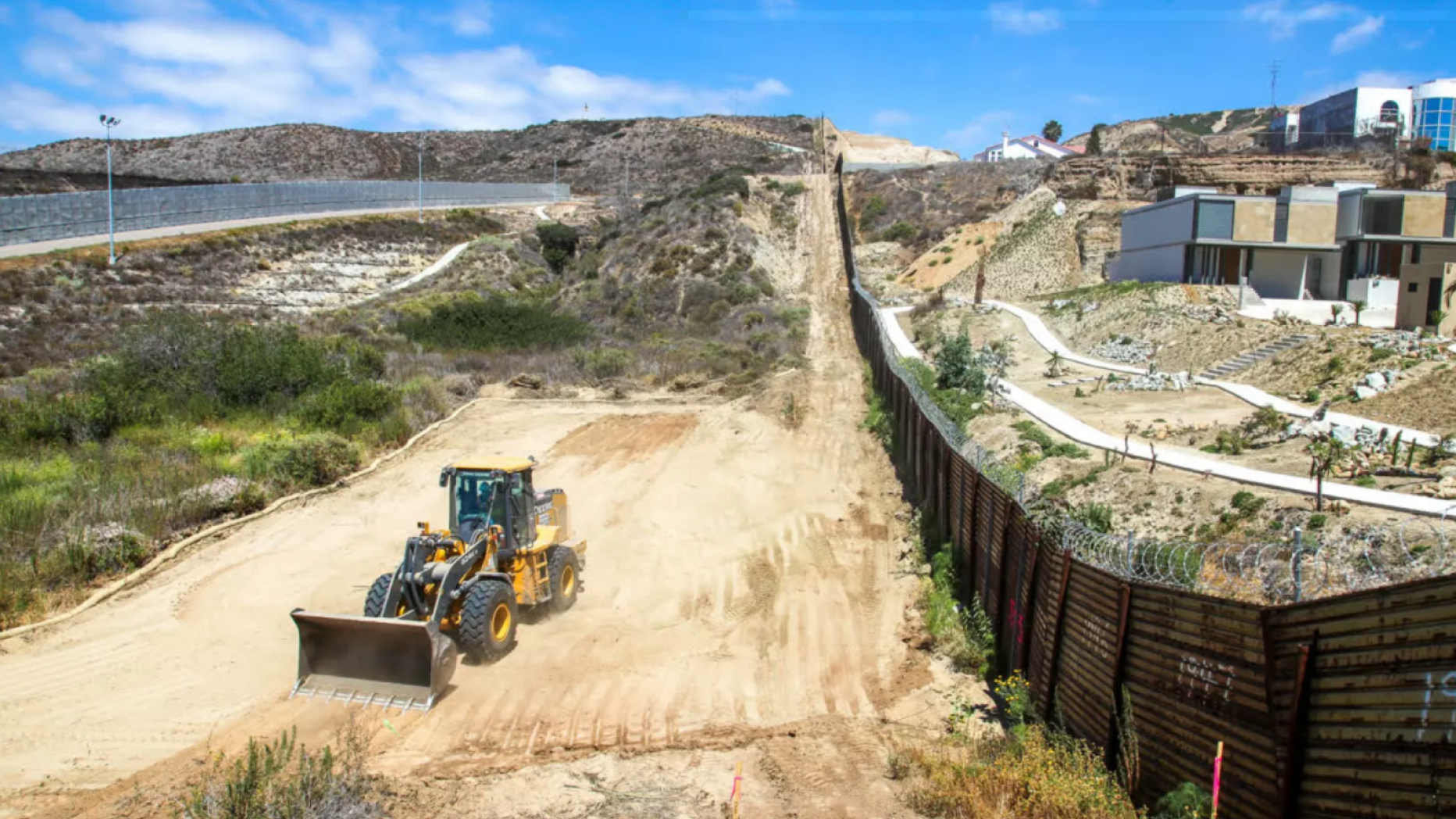 Bulldozer in desert next to fence