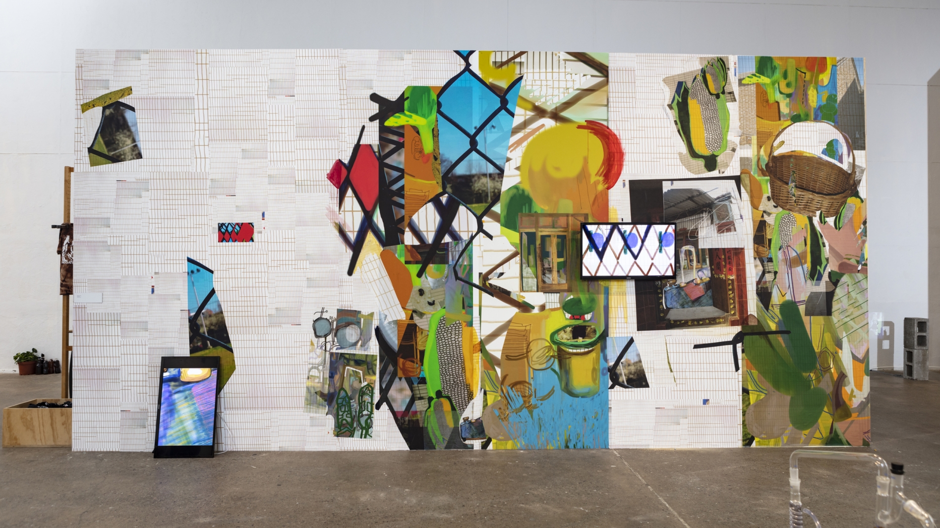 Mural wall with abstract collage of colors and patterns with screens displaying similar imagery