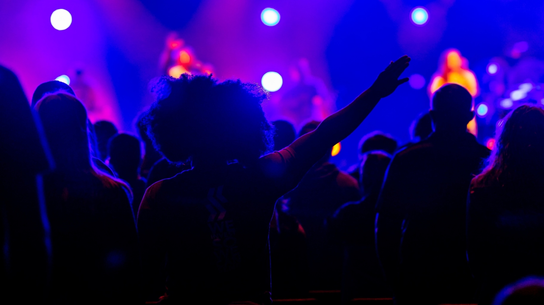 Crowded nightclub, people dancing and bright purple lights flashing.