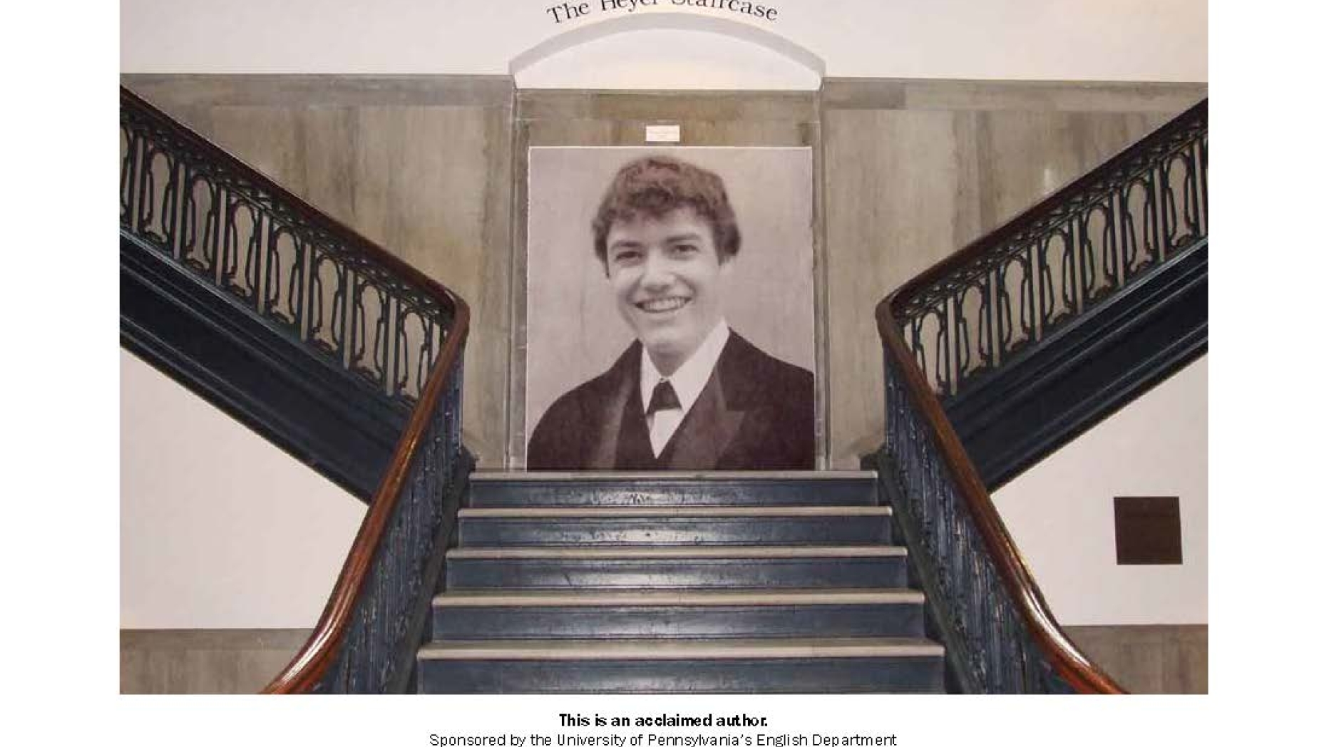 Installation piece where a large black and white photo of a young man has been place at the center of a staircase. Above the photo in and archway is the text "The Heyer Staircase"