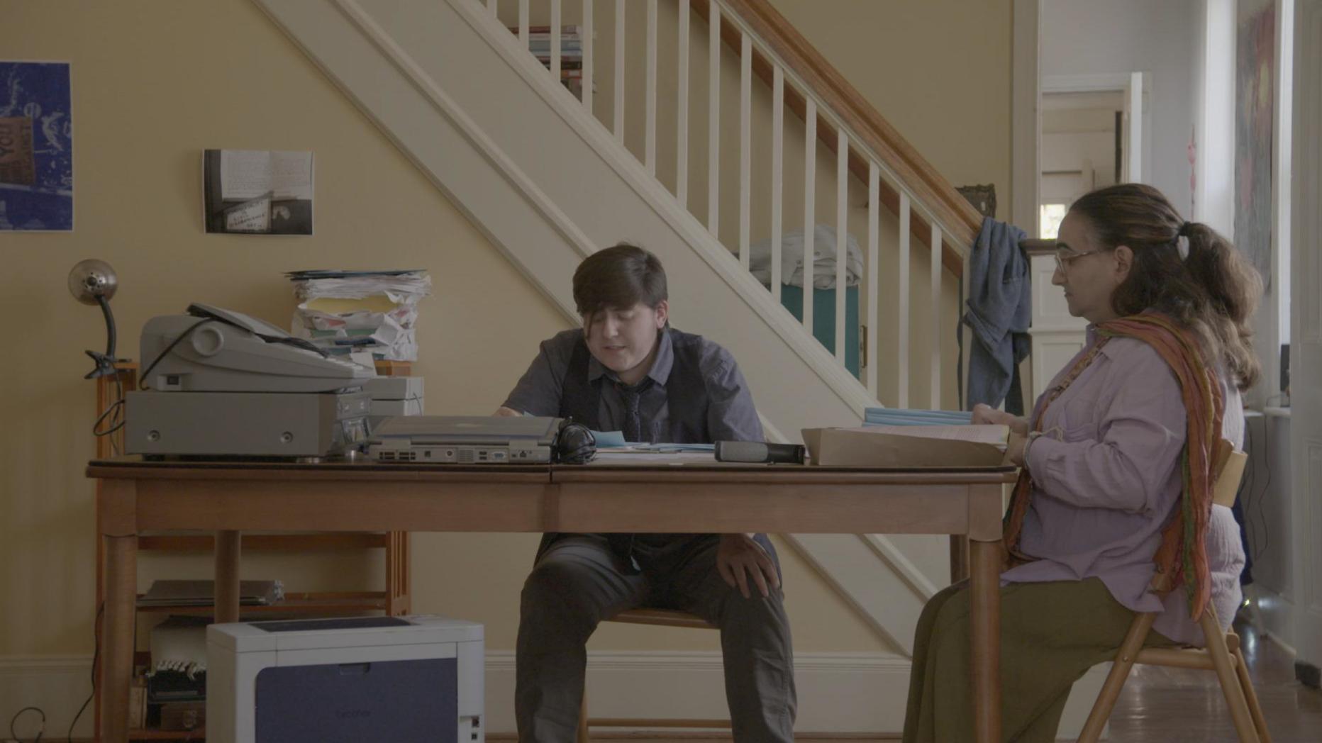 Woman and boy sitting at a table reading 