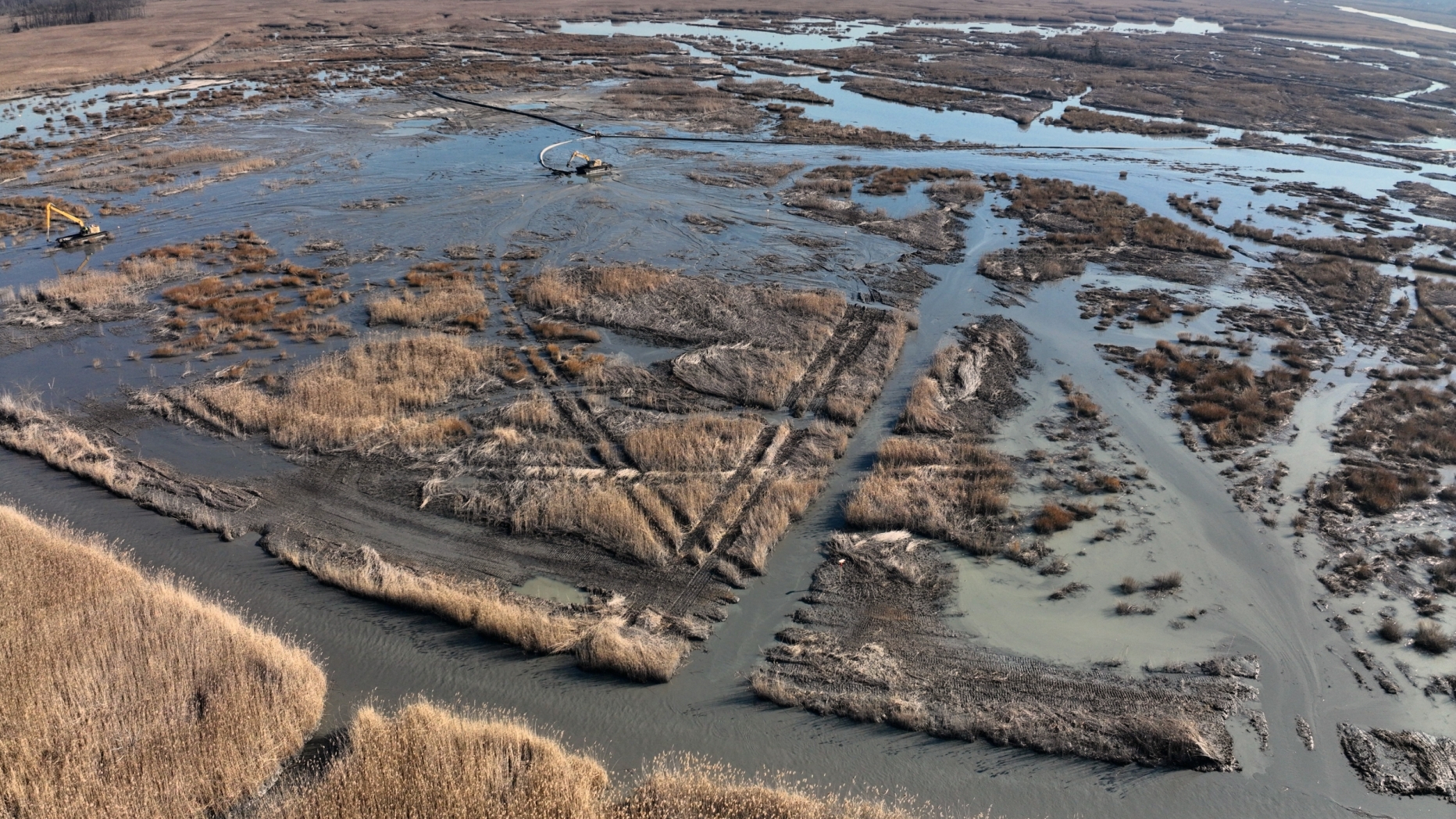 Aerial view of brown marshlike landscape with heavy equipment at work