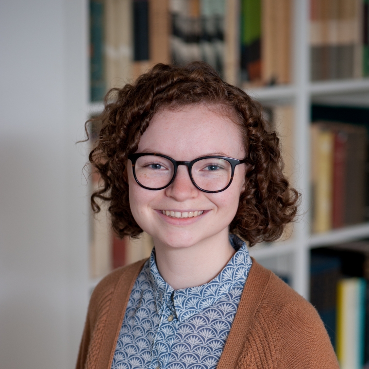 Caroline Reger headshot in front of bookshelves