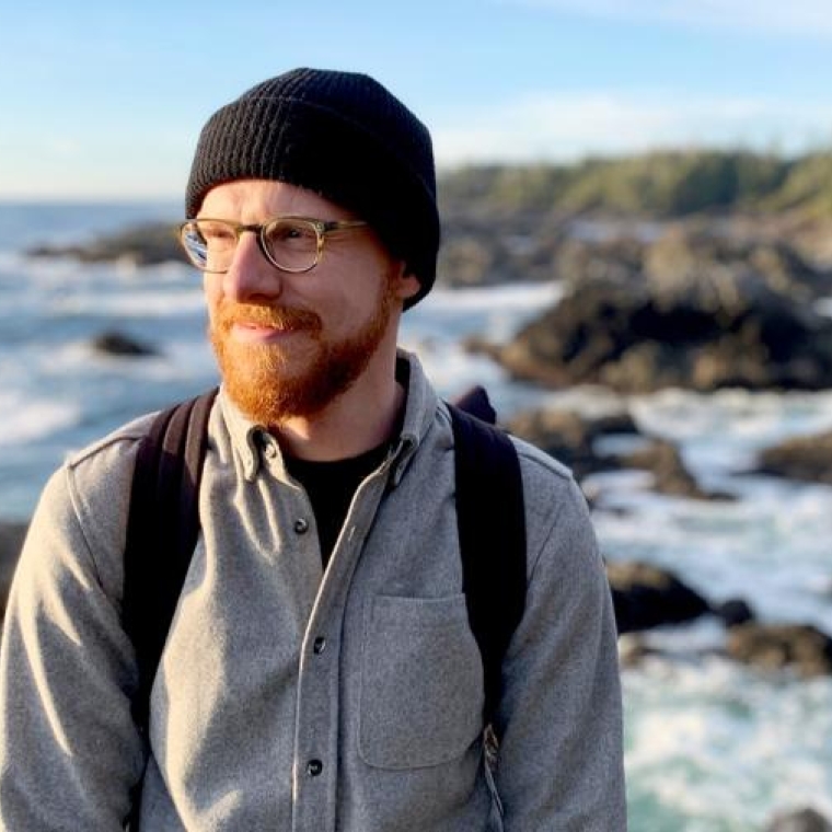 Douglas Robb facing the left hand side into the sun in front of a shoreline