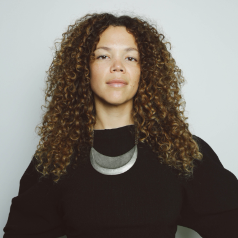 headshot of Allison with hands on her hips, plain black top and statement jewelry 