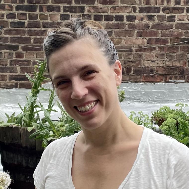 Smiling headshot of Gallun in white blouse, standing in front of brick wall