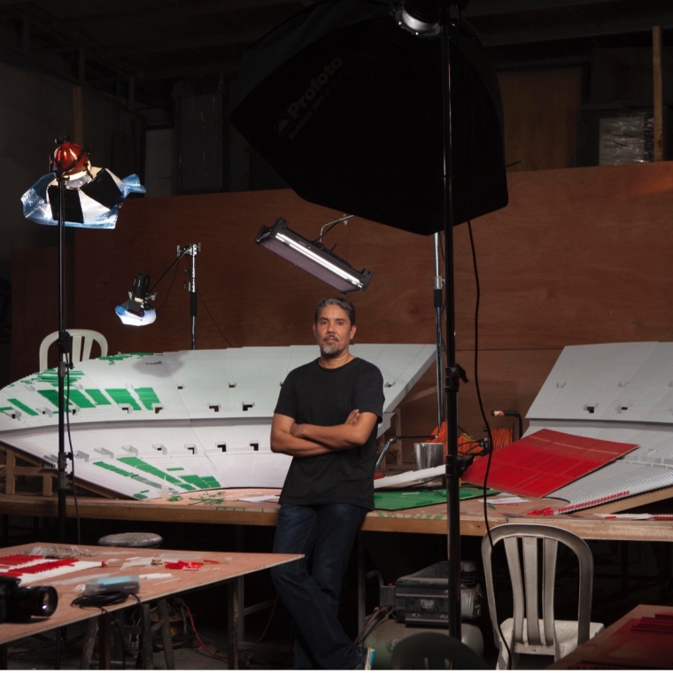 Photograph of Paul Pfeiffer in his studio in front of a sculpture lit up with various professional lighting equipment