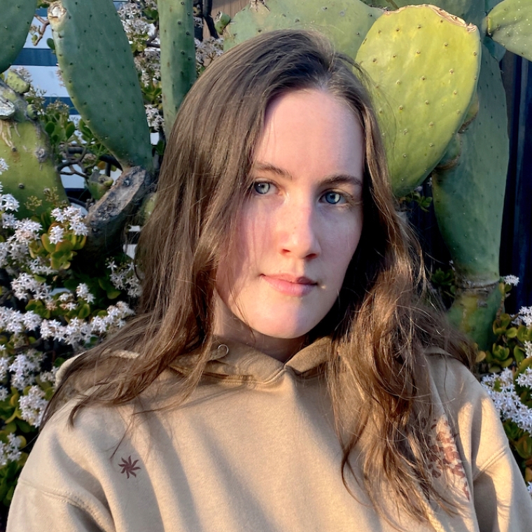 Photograph of Rain Jacobson standing in front of a cactus