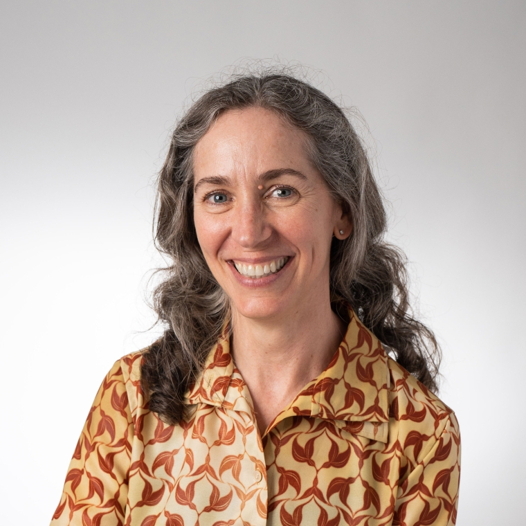 An image of Catherine Seavitt wearing a yellow button down with a brown pattern, against a white background