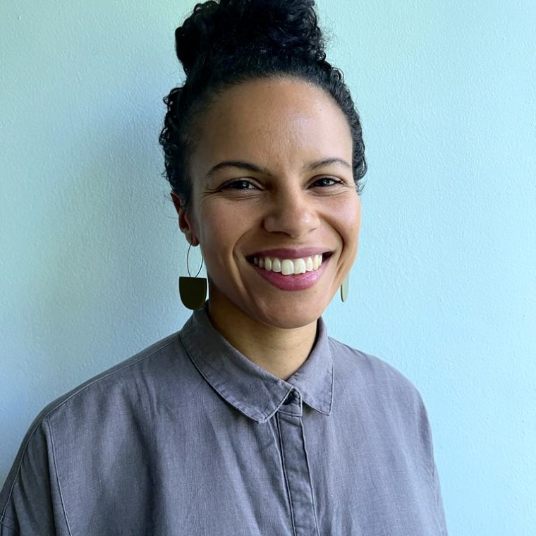 azzurra is smiling in a blue button down shirt in front of a light blue backdrop